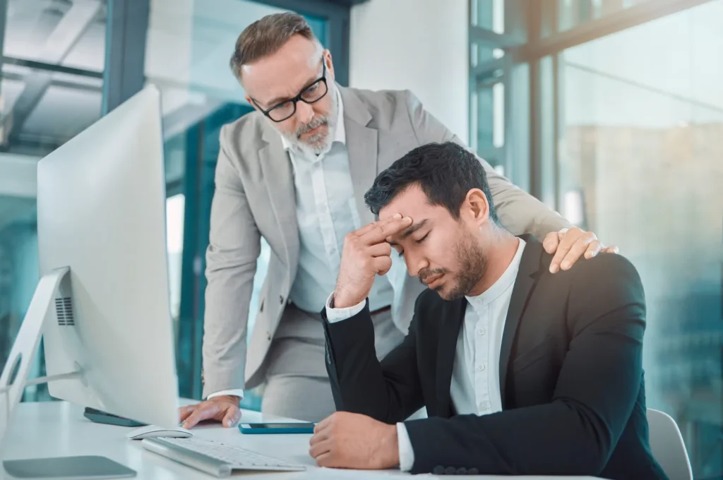 Manager with his hand on the shoulder of a distressed colleague at work